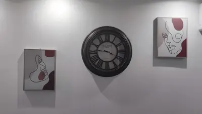 a clock on a wall with pictures of women at Miljakovački konak in Belgrade
