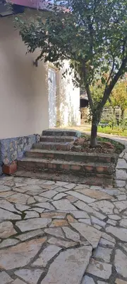 a stone walkway with a tree and a building at Miljakovački konak in Belgrade