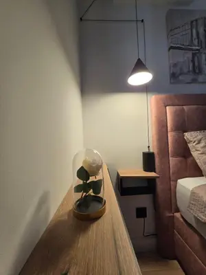 a glass jar with a plant on a table next to a bed at DM apartman Belgrade Waterfront in Sajmište