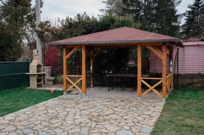 a wooden gazebo with a table in a yard at Vila Banstolija in Velika Remeta