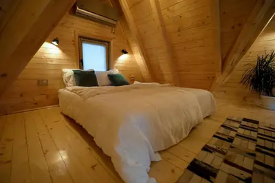 a bedroom with a large bed in a wooden cabin at Vila Banstolija in Velika Remeta