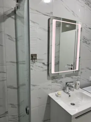 a bathroom with a sink and a mirror and a shower at Apartman Aranđelovac in Arandjelovac