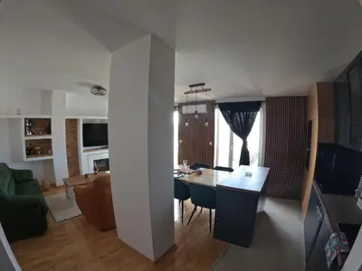 a kitchen and living room with a table and chairs at Bella Lux Centar in Mladenovac
