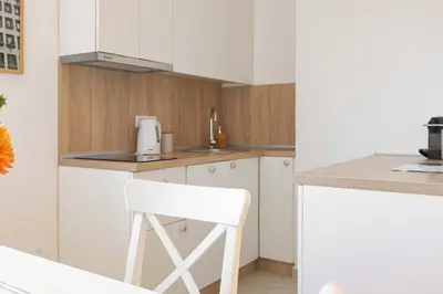 a kitchen with white cabinets and a white chair at Apartment Artistique in Belgrade