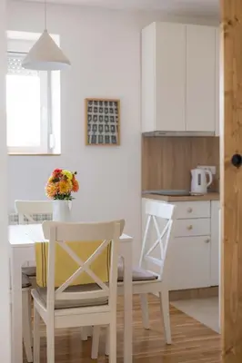 a white kitchen with a white table and chairs at Apartment Artistique in Belgrade