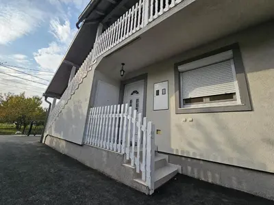 a house with a white fence next to a door at Airport Apartment in Surčin