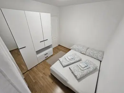 a small white room with a bed and a cabinet at Airport Apartment in Surčin