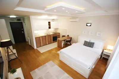 a bedroom with a white bed and a kitchen at Apartment A Block Nota Delta City New Belgrade in Novi Beograd