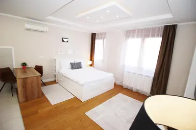 a white bedroom with a bed and a table at Apartment A Block Nota Delta City New Belgrade in Novi Beograd