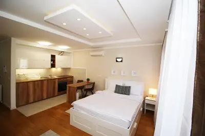 a bedroom with a white bed and a kitchen at Apartment A Block Nota Delta City New Belgrade in Novi Beograd