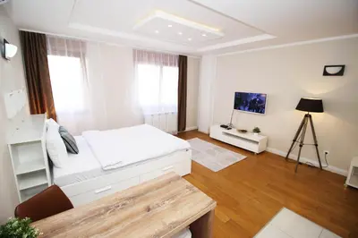 a white bedroom with a bed and a table at Apartment A Block Nota Delta City New Belgrade in Novi Beograd