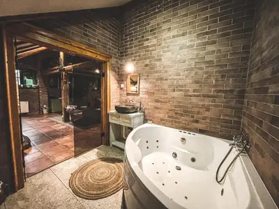a bath tub in a bathroom with a brick wall at Wood Mood Apartman Tiganjica in Staji°evo