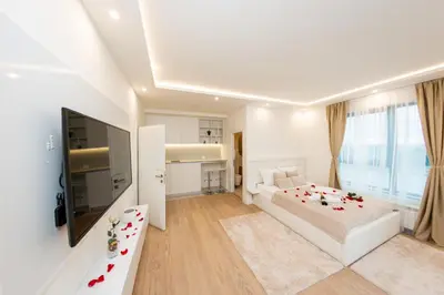a white bedroom with a bed and a flat screen tv at SINFONIA LUX in Belgrade