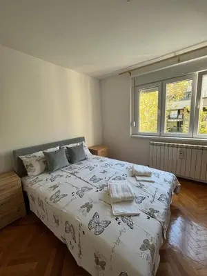 a bedroom with a bed and two windows at MinuteToRiver Apartment in Belgrade