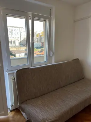 a couch sitting in a room with two windows at MinuteToRiver Apartment in Belgrade