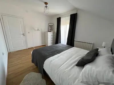 a bedroom with a large white bed and a window at Apartman Magnolia in Zemun