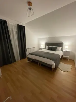 a bedroom with a large bed and wooden floors at Apartman Magnolia in Zemun