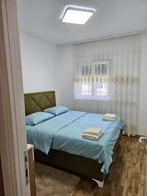 a bedroom with a bed with blue sheets and a window at Apartman Meggy in Belgrade