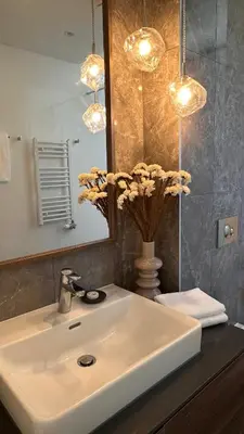 a bathroom sink with a mirror and a vase with flowers at DOM Boutique Apartments VERDE in Belgrade