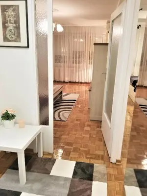 a living room with a white table and a hallway at Arena West Apartment in Novi Beograd