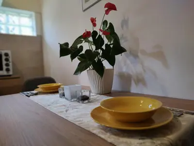 a table with two yellow plates and a vase with red flowers at Apartman Orhideja in Novi Banovci