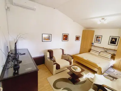 a room with a bed and a couch and a chair at Apartman Orhideja in Novi Banovci
