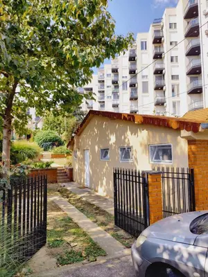 a building with a fence in front of a tall building at Apartman Orhideja in Novi Banovci