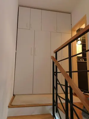 a kitchen with white cabinets and a staircase at Duplex Delight in Belgrade