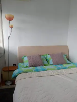 a bed with blue and green pillows and a lamp at Ušće apartman in Novi Beograd