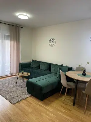 a living room with a green couch and tables at Cvetanov trg LUX 3 in Belgrade