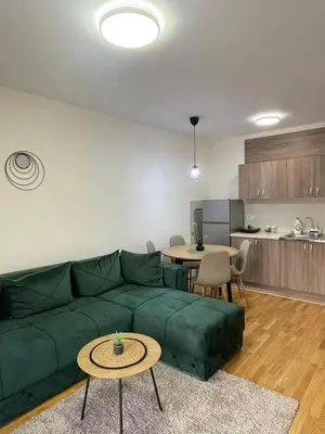 a living room with a green couch and a kitchen at Cvetanov trg LUX 3 in Belgrade
