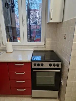 a kitchen with a stove and red cabinets and a window at Belgrade City Center Apartment in Belgrade