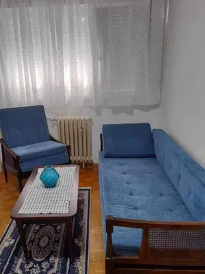 a living room with two blue couches and a table at Sobe Aerodrom in Surčin
