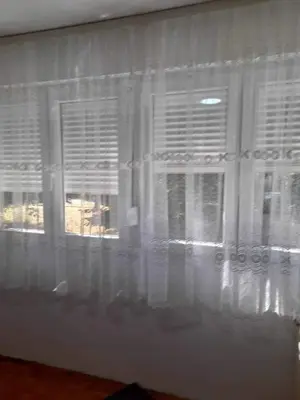 a window with white curtains in a room at Sobe Aerodrom in Surčin