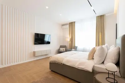 a bedroom with a large bed with a television on a wall at Olive Apartments in Belgrade