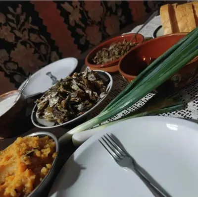 a table with plates and bowls of food and utensils at Etno domaćinstvo Miris Bosiljka in Mislođin