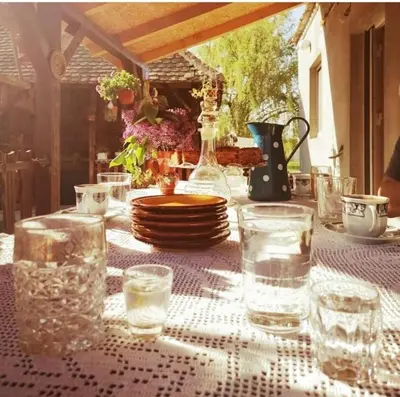 a table with a white table cloth with glasses on it at Etno domaćinstvo Miris Bosiljka in Mislođin