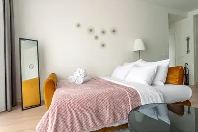 a bedroom with a bed with a pink blanket and a mirror at The View Belgrade Waterfront in Belgrade