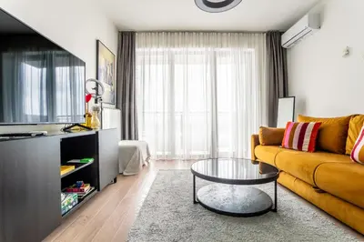 a living room with a yellow couch and a glass table at The View Belgrade Waterfront in Belgrade