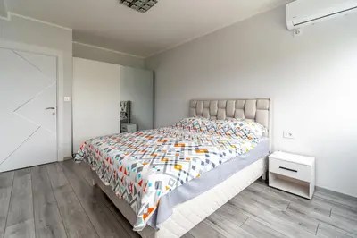 a bedroom with a large bed and a white wall at Apartman Ivana in Novi Beograd