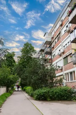 a person walking down a sidewalk next to a building at Apartman Ivana in Novi Beograd