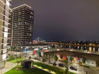 a view of a city at night with a tall building at Apartman IrMa in Sajmište