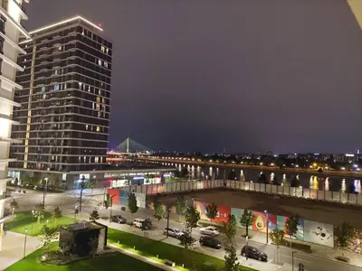 a view of a city at night with a tall building at Apartman IrMa in Sajmište