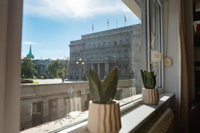 two plants in vases on a window sill with a building at Sweet House Parlament Lux in Belgrade