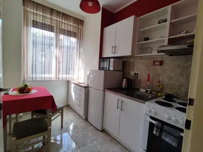 a kitchen with white cabinets and a table with a red table cloth at BGholik studio apartment in Belgrade