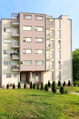 a large apartment building with a lawn in front of it at Antik Apartman in Stara Pazova