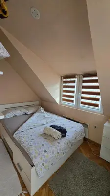 a bed in a room with two windows at Cozy loft in Belgrade