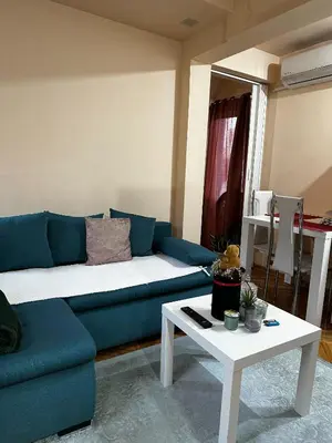 a living room with a blue couch and a table at Cozy loft in Belgrade