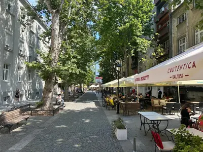a street with tables and chairs and people sitting at tables at Passpartu Apartments in Belgrade