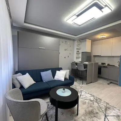 a living room with a blue couch and a kitchen at Apartman Film City in Žarkovo